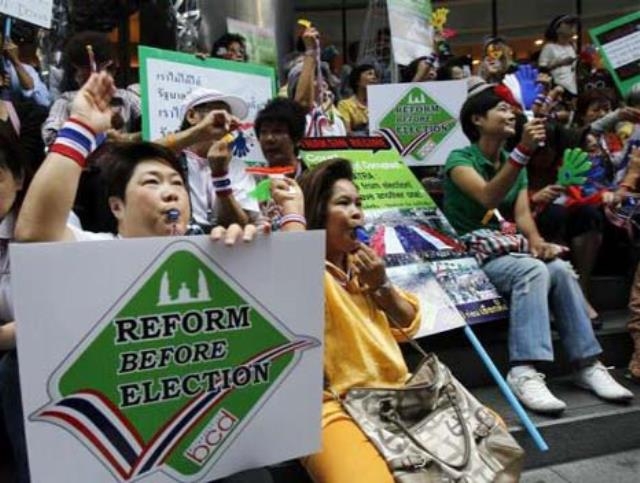 Anti-government protesters blow whistles and hold placards during a rally at Silom road in central Bangkok.