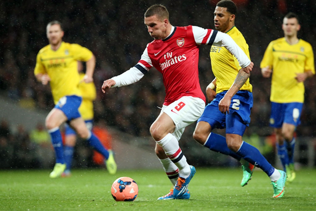 Arsenal's Lukas Poldoski (2nd from left) takes the ball past Coventry's Cyrus Christie, on his way to score his first goal during their fourth round English FA Cup soccer match between Arsenal and Coventry City at the Emirates Stadium in London on Frida