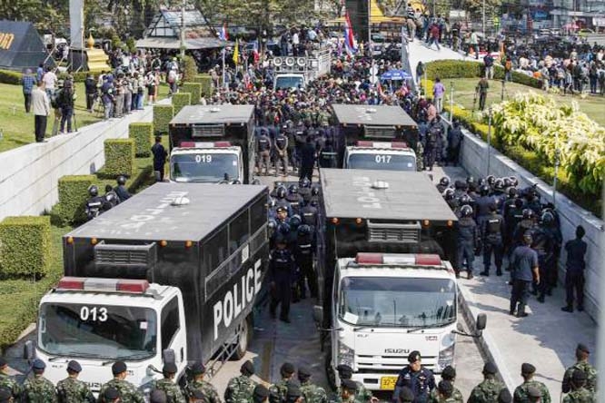 Riot police officers stand guard as anti-government protesters gather at the gates of the Army Club where Thailand's Prime Minister Yingluck Shinawatra is holding a meeting with the Election Commission to discuss plans for a general election on February