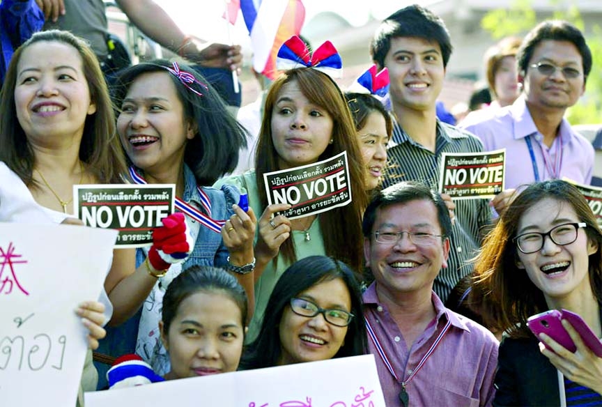 Thai office workers on Friday waiting with banners to greet anti-government protest leader Suthep Thaugsuban during his march to encourage people not to take part in the election.