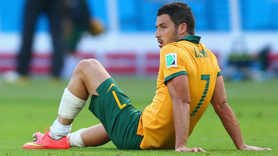 A dejected Mathew Leckie of Australia sits on the field after being defeated by the Netherlands 3-2 during the 2014 FIFA World Cup Brazil Group B match between Australia and Netherlands at Estadio Beira-Rio on Wednesday in Porto Alegre, Brazil.