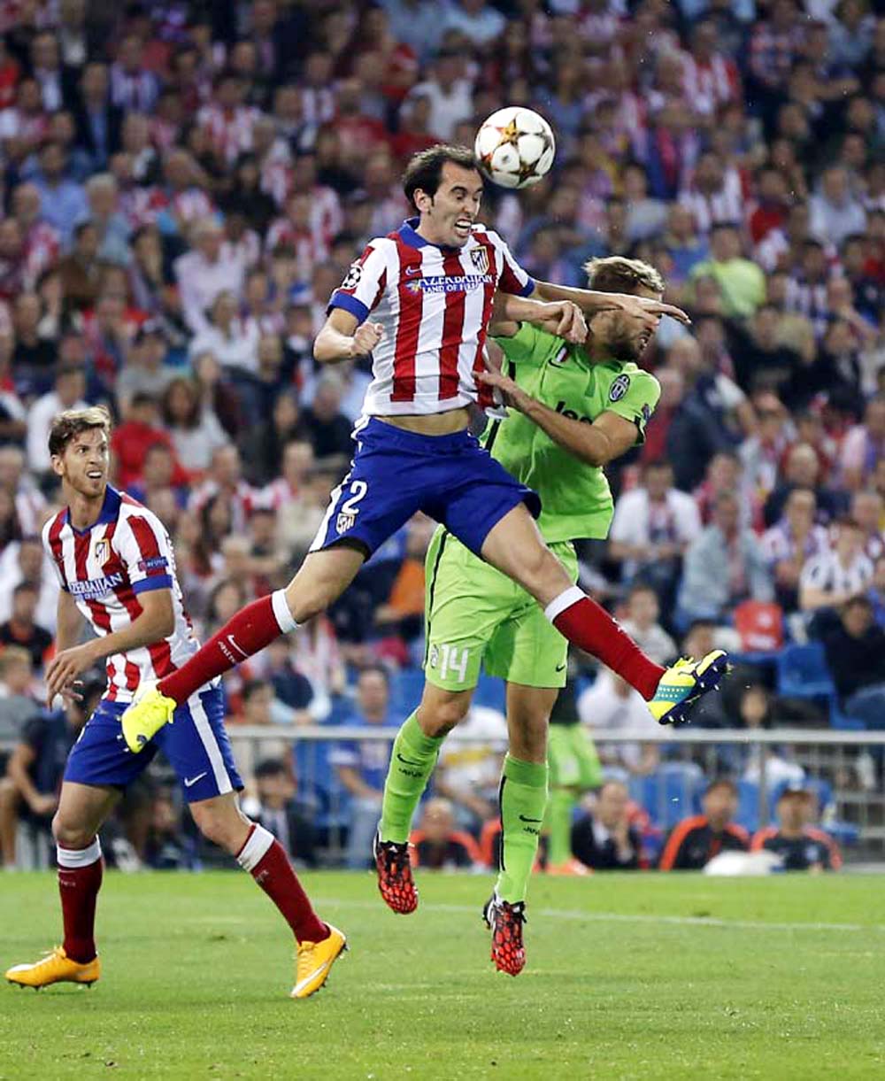 Atletico's Diego Godin, left, goes for a header with Juventus' Fernando Llorente during the Group A Champions League soccer match between Atletico De Madrid and Juventus at the Vicente Calderon stadium in Madrid, Spain onWednesday.